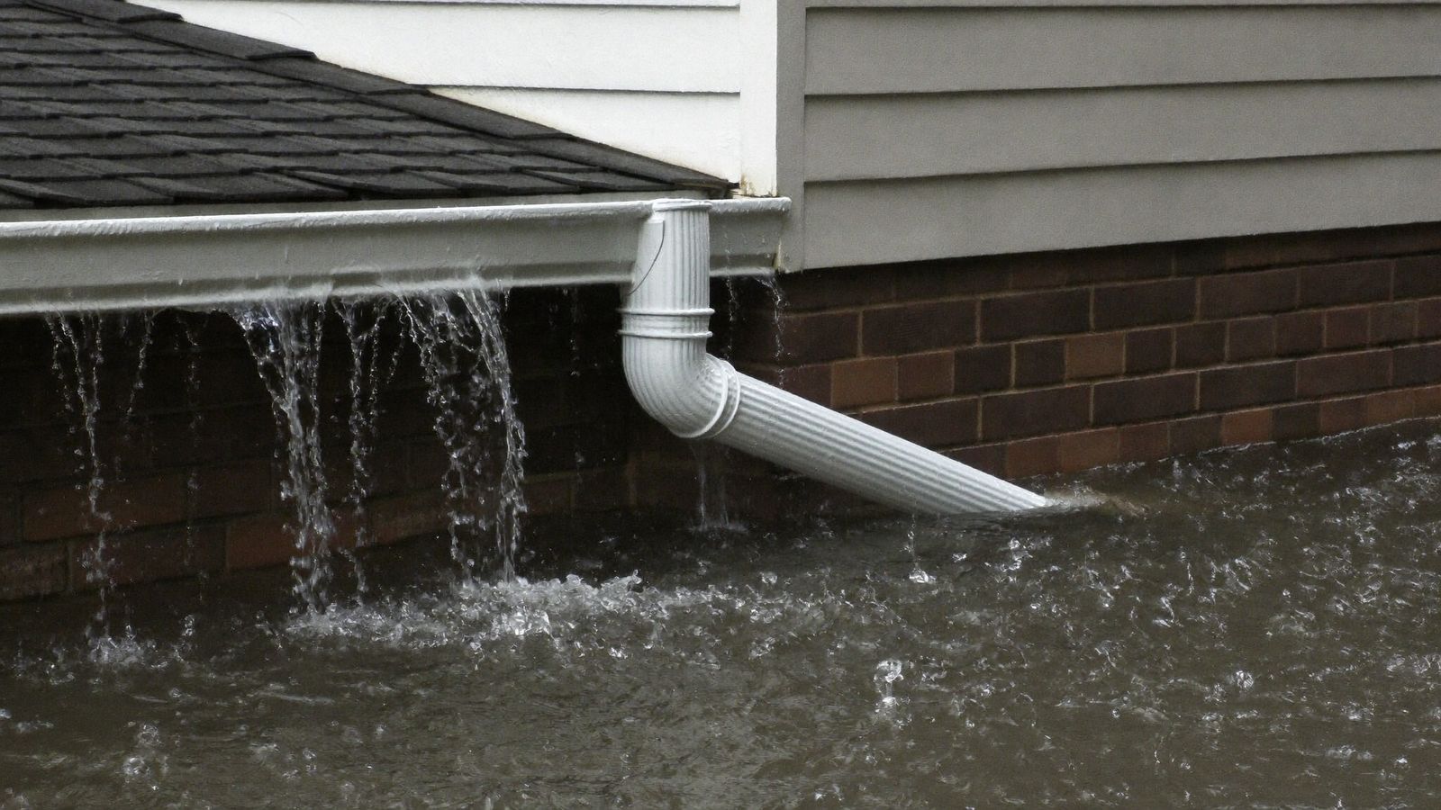 Rainwater overwhelming gutters and a downspout during a Houston downpour